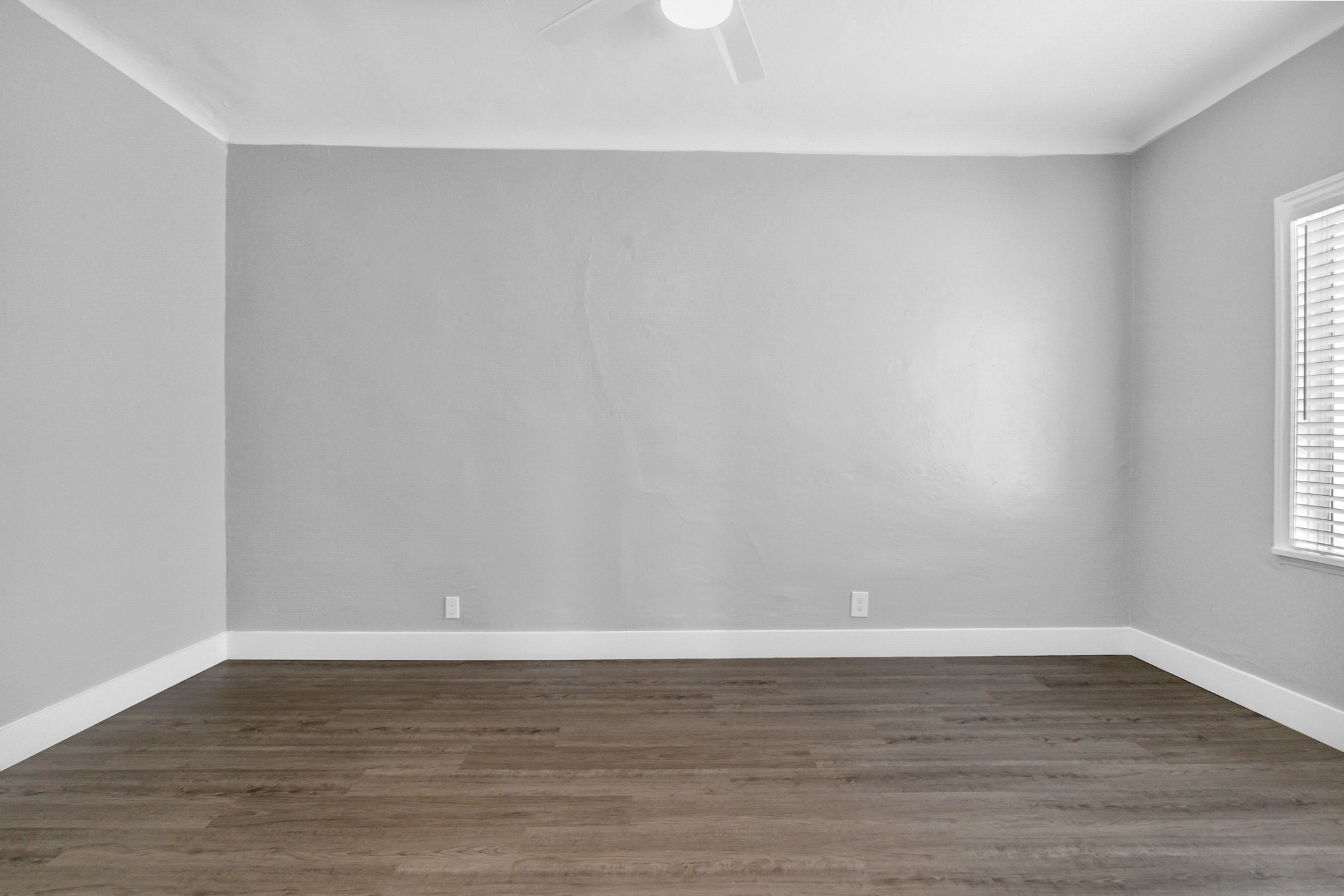 A room with wooden flooring and a ceiling fan.